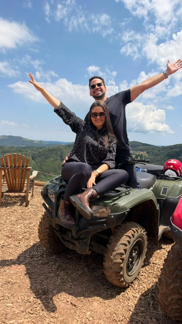 Casal de braços abertos no quadriciclo no mirante Mão de Deus em Monte Verde