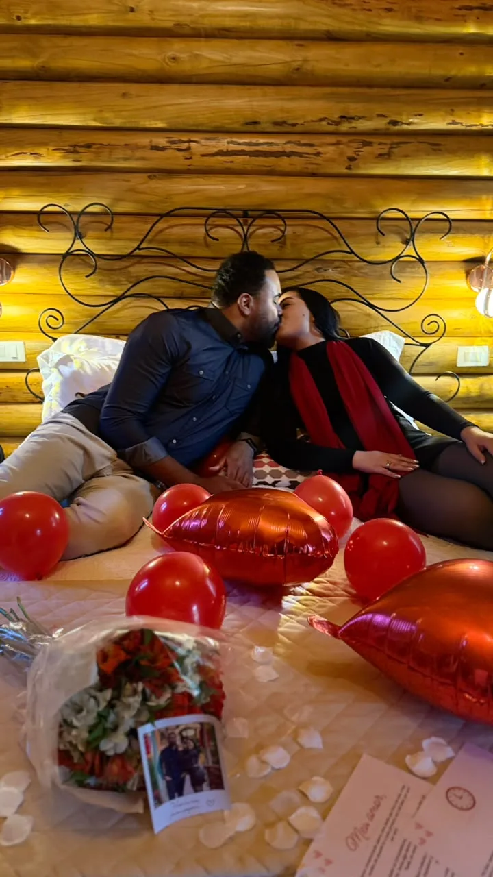 Casal se beijando no quarto decorado com balões e pétalas em Monte Verde