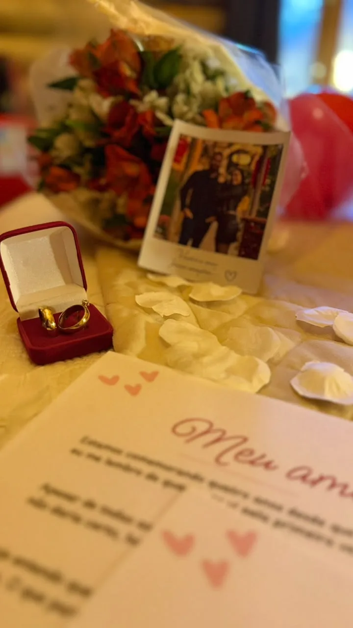 Buquê de flores, carta e alianças preparados para a celebração do casal
